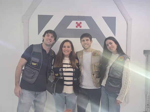 Cuatro personas posando juntas, con ropa casual y sonrisas, en un entorno interior.