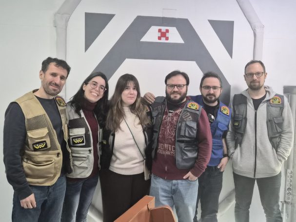 Grupo de seis personas con chalecos en un entorno interior.